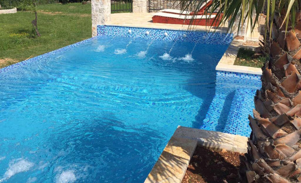 Design-Betonpool 5×2,5 m mit Mosaikfliesen in Türkistönen.